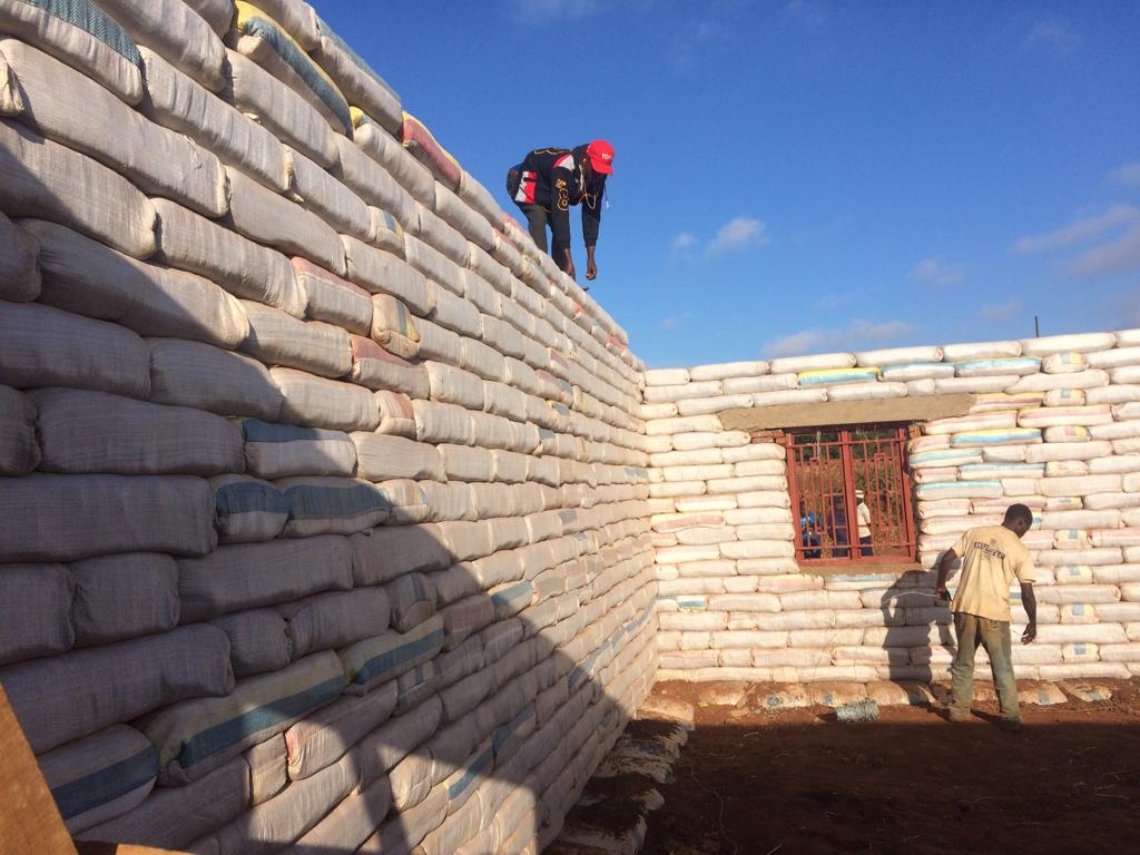 Foundations being laid from stacked cement bags at sunset
